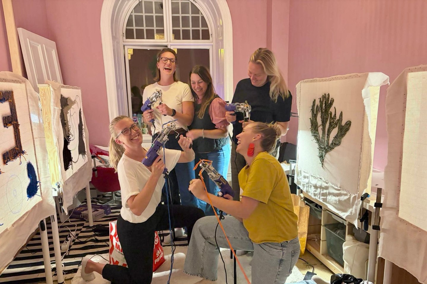 Fem deltagare som skrattar och posar med sina tuftpistoler i ullipeys studio
